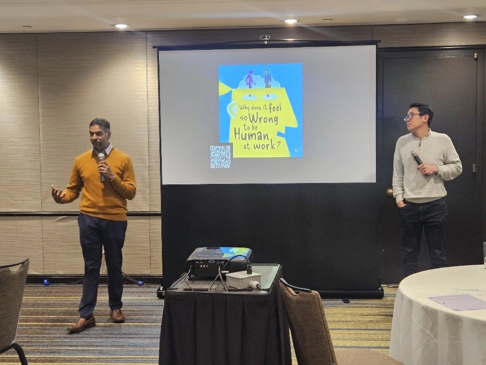 Pinaki Kathiari and Chris Lee on stage under the Human at Work podcast slide