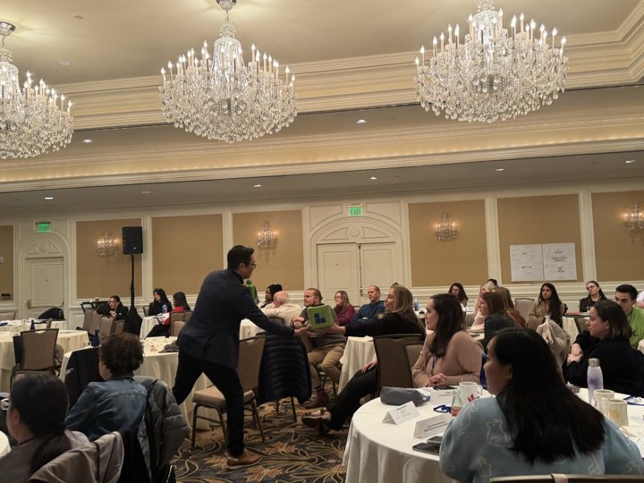 A host moving among the round tables during the Human at Work un-panel